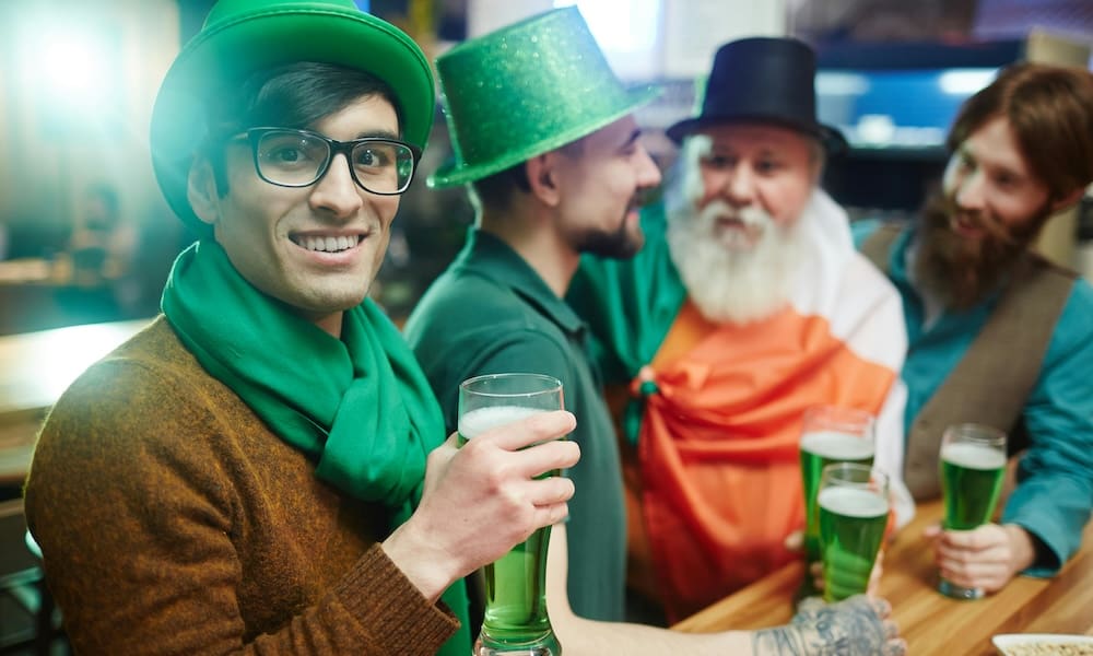 multicultural friends watching tv and clinking glasses, saint patrick day concept
